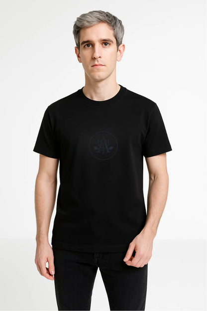 Young man with gray hair wearing black t-shirt with subtle logo on front against white background