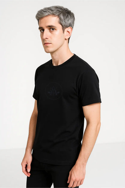 Young man with gray hair wearing a black t-shirt featuring a subtle logo on white background